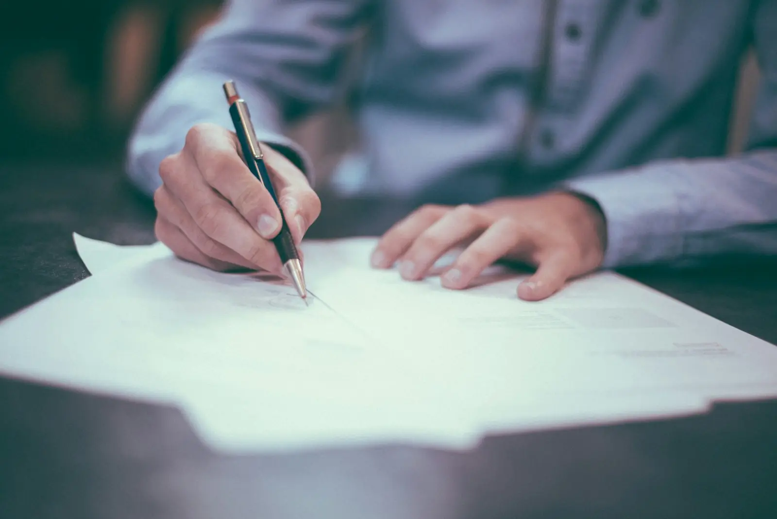 Hands signing a paper document