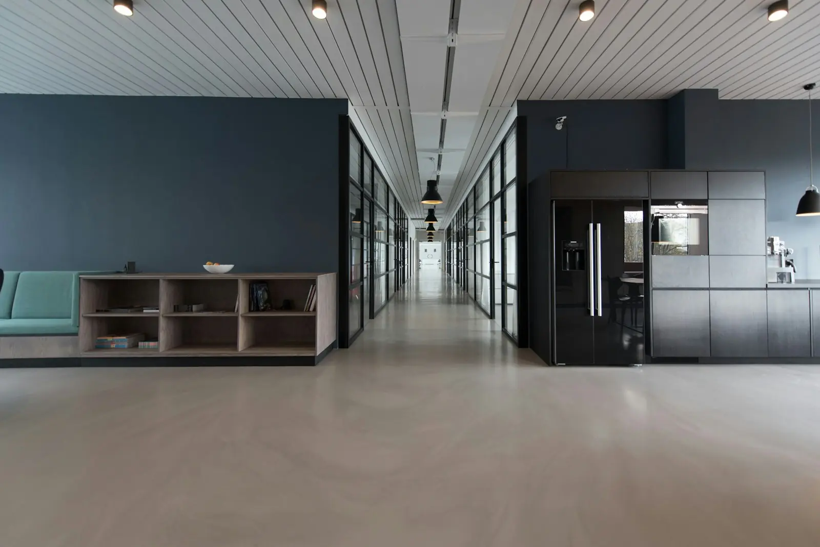 A bright office hallway with glass meeting rooms