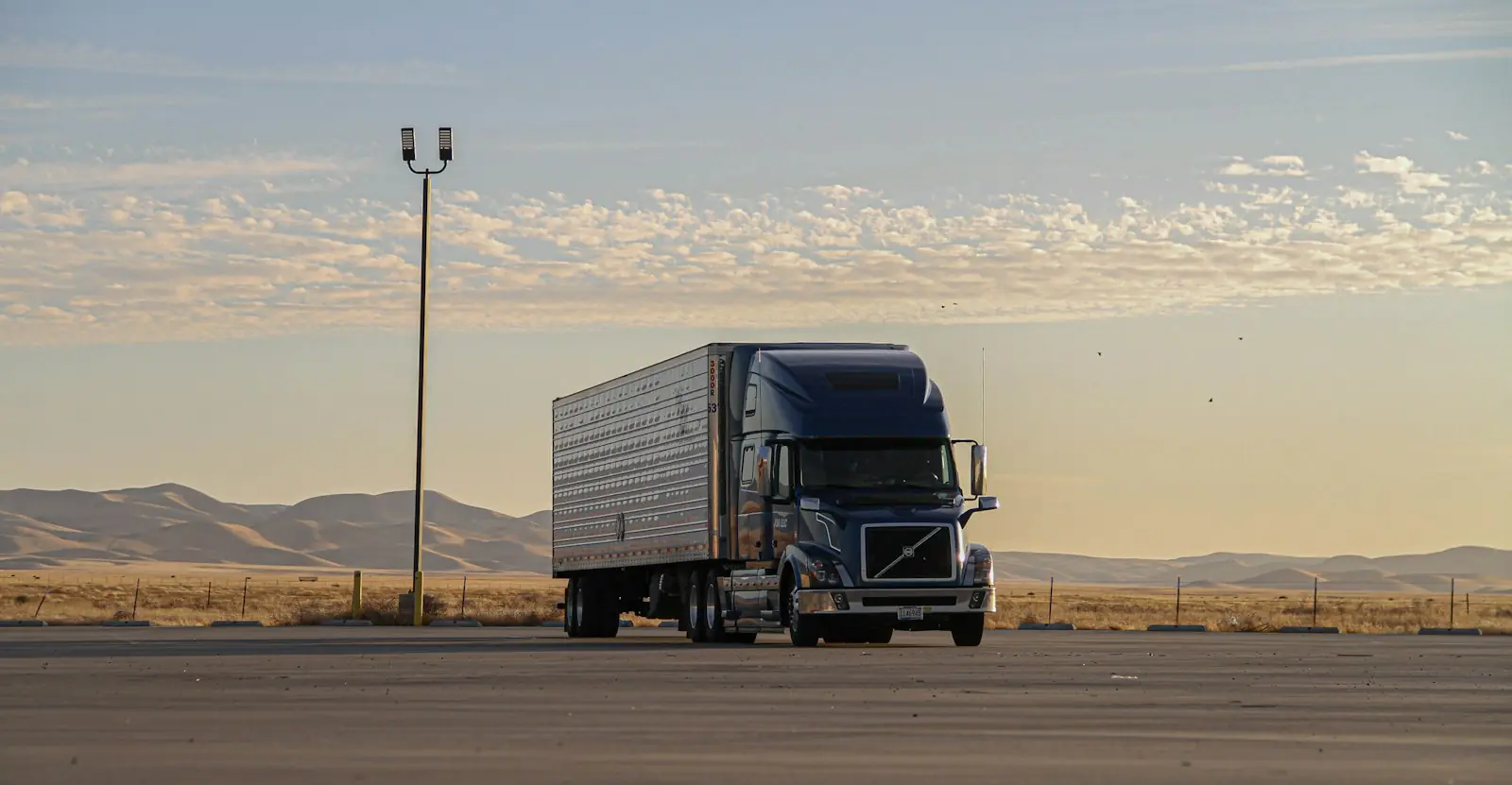 A tractor-trailer parked on an open lot at dusk